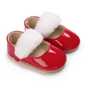Primo piano di scarpe da neonato in vernice rossa con pompon in ecopelliccia bianca - Rosso