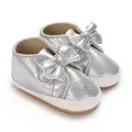 Détail de chaussures argentées pailletées pour bébé avec nœuds et semelles souples - Argent