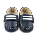 Makro-Detailansicht von dunkelblauen Kunstleder-Babyschuhen mit weißen Streifen. - Blau