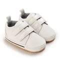 Detail view of white baby walking shoes with double Velcro straps and anti-slip sole - White
