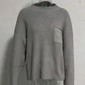 Gros plan d'un pull en maille gris à col rond avec une poche de poitrine détaillée - Gris
