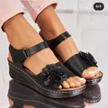 Nahaufnahme schwarzer Keilsandalen mit floralen Mustern auf einer Plateausohle - Schwarz