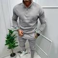 Full view of grey men's quarter-zip tracksuit set worn by model in casual indoor setting. - Light Gray