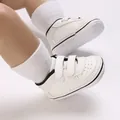 Detail view of white anti-slip baby walker shoes with Velcro straps and dotted sole. - Black