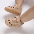 Close-up of beige baby shoes with heart cutouts and non-slip soft soles on model legs. - Apricot