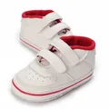 Close-up view of white and red infant walking shoes with non-slip rubber soles - Red