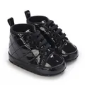 Nahaufnahme von schwarzen Lackleder-Babyschuhen mit gestepptem Muster für Jungen - Schwarz