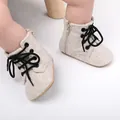 Gros plan sur des chaussures de marche bébé en toile beige avec lacets noirs et zip - Abricot