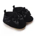Close-up detail of black velvet infant walking shoes featuring elegant satin bows - Black