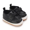 Dettaglio di scarpe da ginnastica nere testurizzate per neonati con suola morbida e velcro - Nero