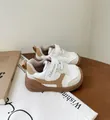 Primer plano de zapatos para bebé en blanco y marrón con velcro y suela muy blanda - Caqui