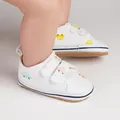 Gros plan de chaussures de marche pour bébé en toile blanche avec motifs de voitures - Jaune