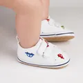 Gros plan de chaussures de marche blanches pour bébé avec motifs de voitures et velcro. - Vert & Rouge