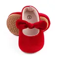 Close-up of red velvet baby shoes with a prominent bow and textured rubber sole - Red