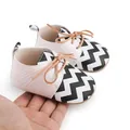 Close-up of baby walker shoes with black and white zigzag pattern and tan laces - Striped White (2193)