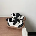 Black and white toddler sneakers with soft brown rubber soles and hook-and-loop straps. - Black