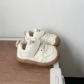 Cream-colored toddler walking shoes with soft rubber soles and Velcro straps for infants. - Beige