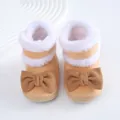 Primer plano detallado de botas suaves para bebé con lazos marrones y piel cálida - Café