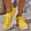 Close-up of vibrant yellow breathable fly-knit sneakers with white sole on wooden floor - Yellow