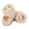Primer plano de botas de invierno beige para bebé con forro de felpa y bordado de oso. - Marrón