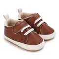 Close-up of brown faux leather baby sneakers with white laces and soft soles - Brown