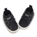Nahaufnahme von schwarzen Babyschuhen mit 'BABY' Klettverschluss und weißer weicher Sohle - Schwarz