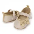 Detailansicht glitzernder beiger Baby-Prinzessinnenschuhe mit Satinschleife und Riemen. - Gold