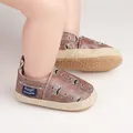 Gros plan de chaussures de marche pour bébé avec motif moustache et étiquette tissée - Café