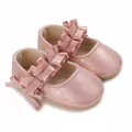 Primer plano de zapatos de princesa rosa brillante para bebé niña con volantes y lazo - Rosa