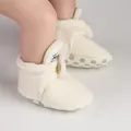 Detailed view of warm cream plush baby booties with anti-slip green dotted soles - White