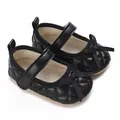 Primer plano de zapatos de bebé acolchados negros con un elegante detalle de lazo - Negro