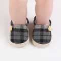 Detalle de zapatos de bebé a cuadros con botones de oso de madera y suela de yute. - Negro