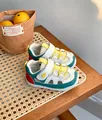 Vista laterale di sneaker per bambini con mesh e dettaglio a cuore su tavolo in rattan - Blu