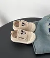 Dettaglio delle scarpine in tela beige per neonato con ricamo Topolino sulla chiusura - Beige