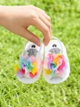 Détail de sandales blanches pour bébé avec fleurs en maille colorées sur l'herbe - Ivoire Avec Fleurs Colorées
