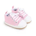 Primer plano de zapatos de lona rosa para bebés con cordones blancos y puntera blanca - Rosa