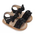 Detailed view of black baby girl sandals featuring ruffles and large bow decorations - Black