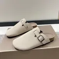 Close-up detail of beige suede clog slippers featuring cork sole and metal buckle - Off White