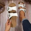 Detailansicht weißer Sandalen mit Krokodilmuster und Metallschnallen auf hellem Holzboden - 35 / Weiß