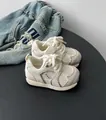 Detailed macro view of cream toddler mesh sneakers with breathable texture and soft soles - Beige
