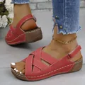 Detail view of stylish red wedge sandals with cross-strap design and white stitching. - Burgundy