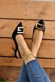 Elegant black pointed-toe slingback high heels featuring a bold gold geometric metal buckle - Black