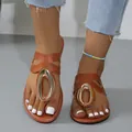 Detailed view of women's brown flat sandals featuring a stylish gold metal buckle. - 36 / Brown