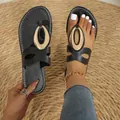 Close-up view of elegant black flat sandals with decorative gold buckle on a woven straw mat. - 36 / Black