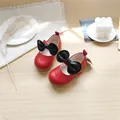 Rote Prinzessinnen-Lederschuhe für Mädchen mit schwarzen Schleifen auf einem Holztisch - Rot