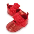 Detailed view of sparkling red glitter baby shoes featuring double fabric flower decorations - Red