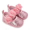 Nahaufnahme von rosa glitzernden Babyschuhen mit drei dekorativen Mesh-Stoffrosen - Rosa