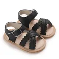 Close-up of black infant sandals with scalloped straps and adjustable buckle detail - Black