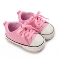 Détail macro montrant la tige en toile rose et l'embout blanc doux des chaussures bébé - Rose