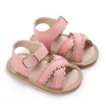 Detailed view of pink baby sandals with scalloped edges and metal buckle hardware. - Pink